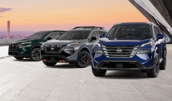 Front view of three 2027 Nissan Rogue SUVs in various trims parked in a bright urban parking lot.