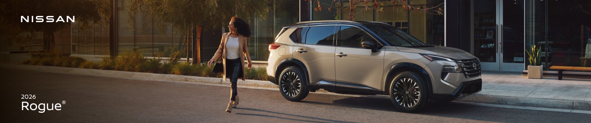 2026 Nissan Rogue Platinum AWD in Champagne Silver Metallic with Super Black roof, front three-quarter view on a city street.